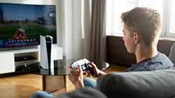 Мальчик сидит на диване и играет в приставку